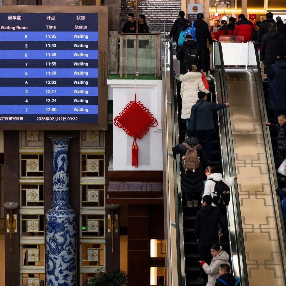 People stand on an escalator next to a screen displaying train information at Beijing Railway Station during annual Spring Festival travel rush, in Beijing, China, February 12, 2026. REUTERS/Maxim Shemetov