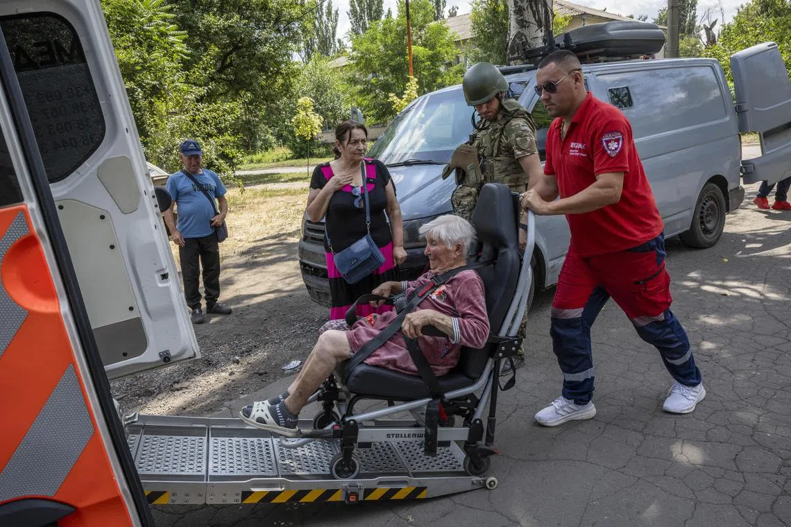 An elderly woman is wheeled into a van during a mandatory evacuation order for the town of Dobropilia, in Ukraine's Donetsk region, on July 26. 