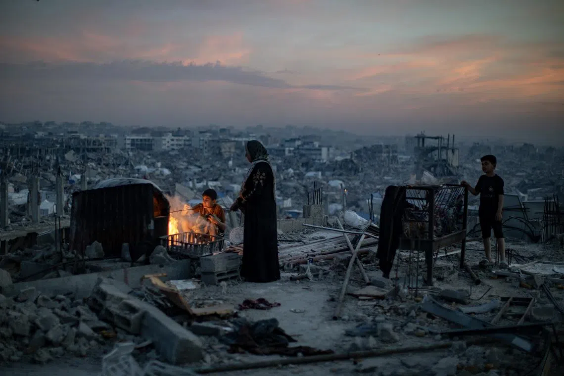 A family gathering for iftar over a fire in the rubble of their destroyed home, during the holy month of Ramadan, in Jabalia refugee camp, northern Gaza Strip, Mar 17, 2025.  