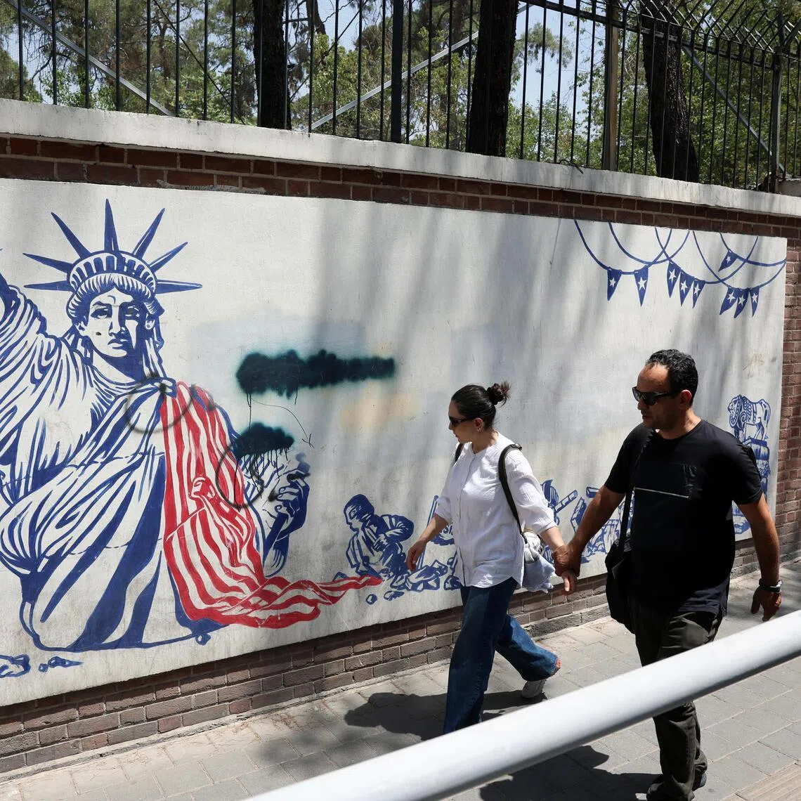 People walking past an anti-US mural next to the former US embassy in Iran’s capital, Tehran, on July 9.