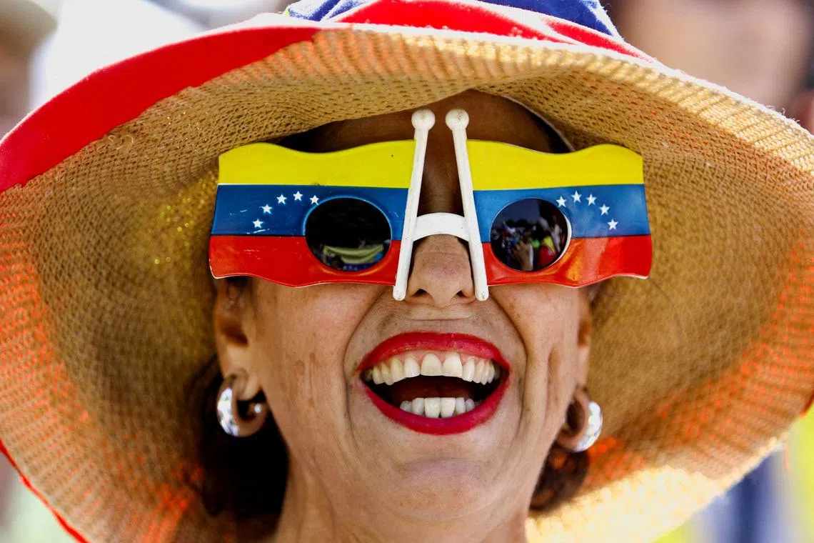 A woman wearing a pair of sunglasses featuring two Venezuelan flags while she takes part in a march calling for amnesty for political prisoners and to mark Youth Day, in Valencia, Venezuela on Febr 12, 2026. 