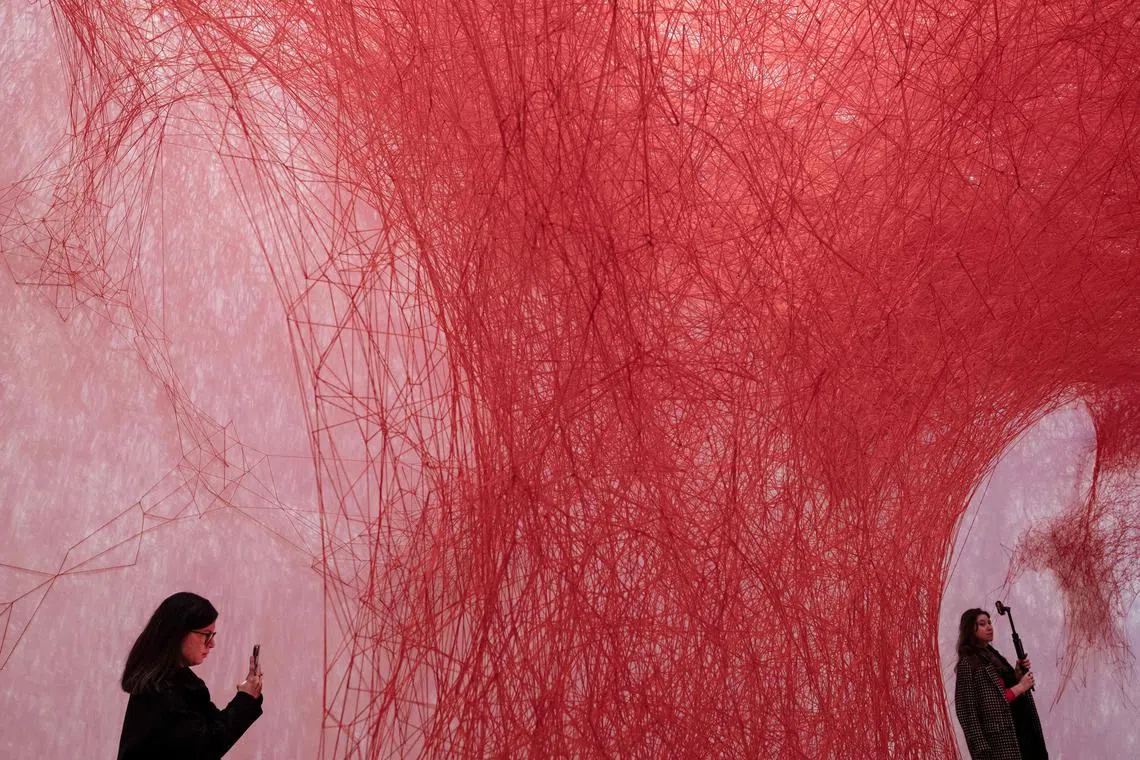 Women taking photographs of an art installation by Japanese artist Chiharu Shiota, titled  "Uncertain Journey", during a press viewing at the Grand Palais in Paris, on Dec 9, 2024.