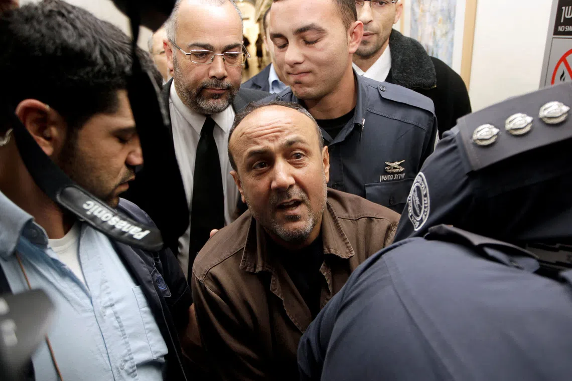 FILE PHOTO: Jailed Fatah leader Marwan Barghouti (C) is accompanied by Israeli prison guards after a deliberation at Jerusalem Magistrate's court January 25, 2012. Convicted of murder for his role in attacks on Israelis, Barghouti was jailed for life by Israel in 2004. REUTERS/Ammar Awad/File Photo