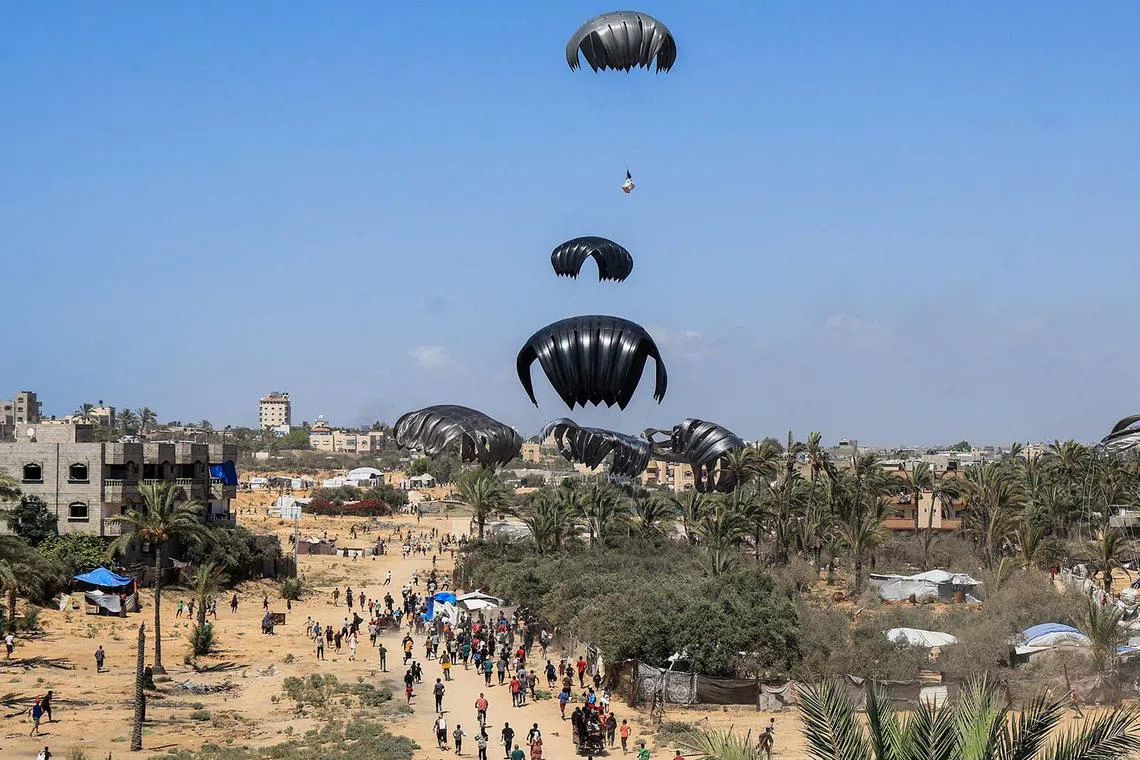 Aid packages dropped from an airplane descending over Gaza, as seen from the central Gaza Strip, July 31, 2025. 
