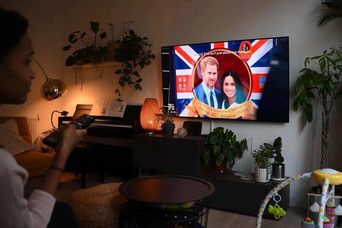 A woman watches an episode of the newly released Netflix docuseries, Harry And Meghan, in London.
