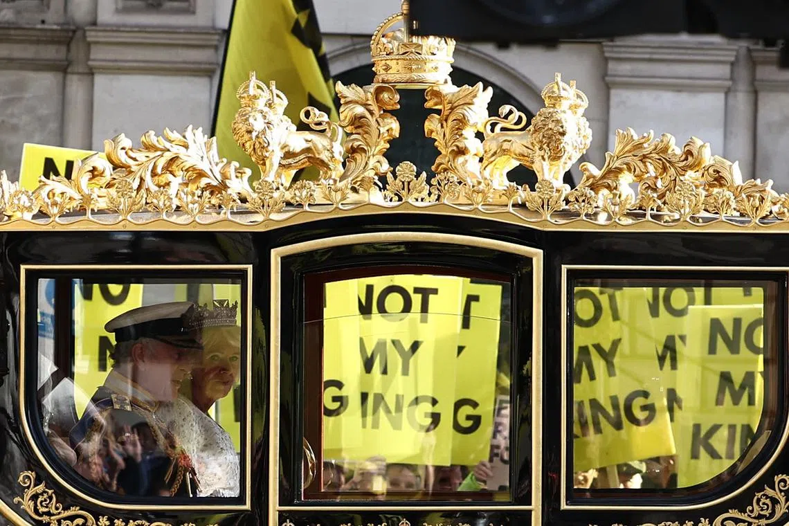 Britain's King Charles III and Britain's Queen Camilla travel in the Diamond Jubilee State Coach past protesters holding "Not My King" placards, from the anti-monarchy group Republic as they demonstrate ahead of the State Opening of Parliament, opposite the Houses of Parliament in London on November 7.