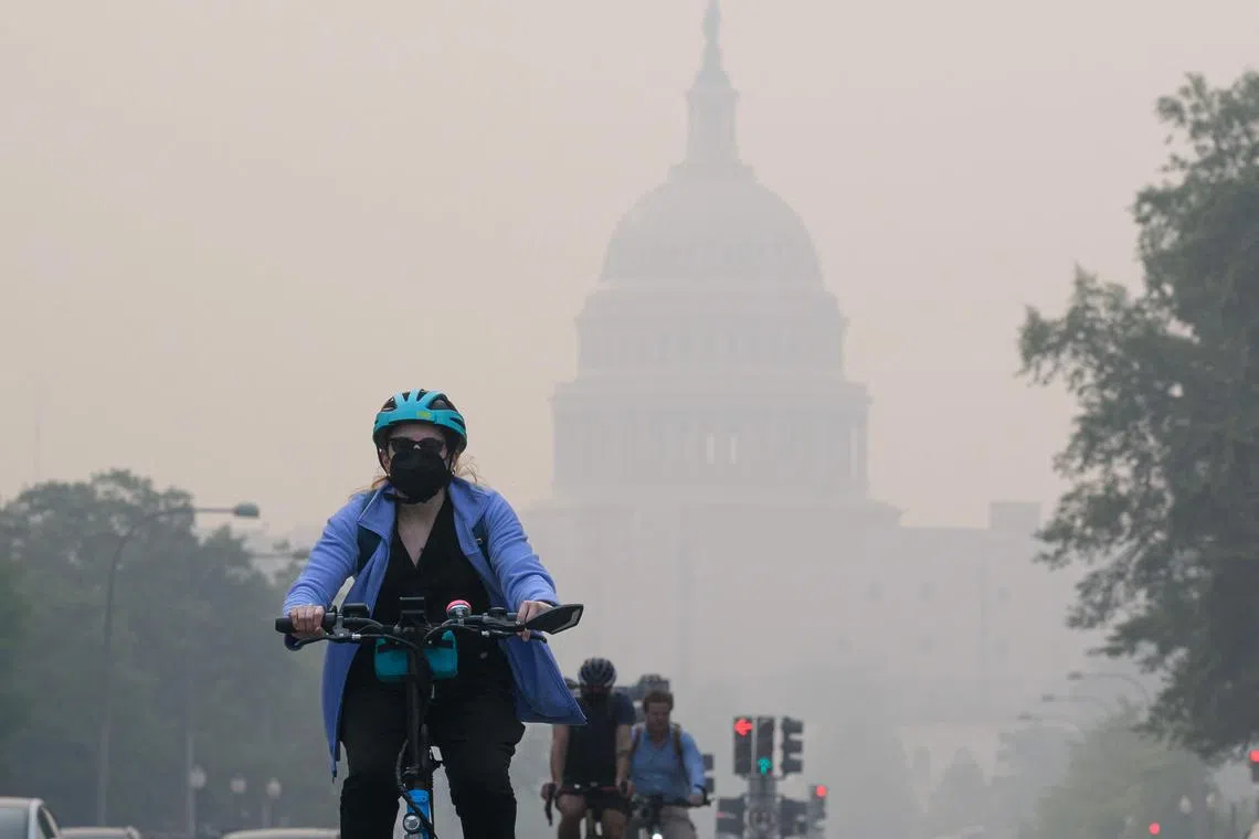A cyclist rides under a blanket of haze from Canada's wildfires, partially obscuring the US Capitol in Washington DC.