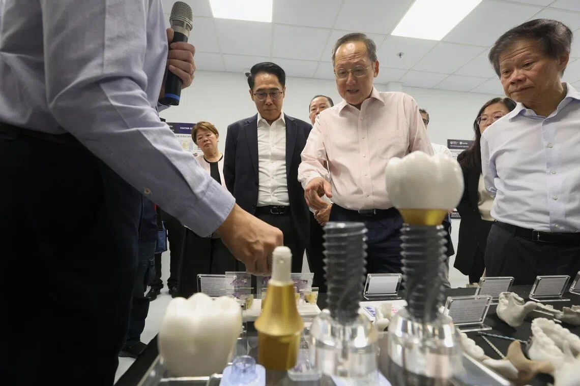 Minister for Manpower Dr Tan See Leng looks at models of tooth implants.