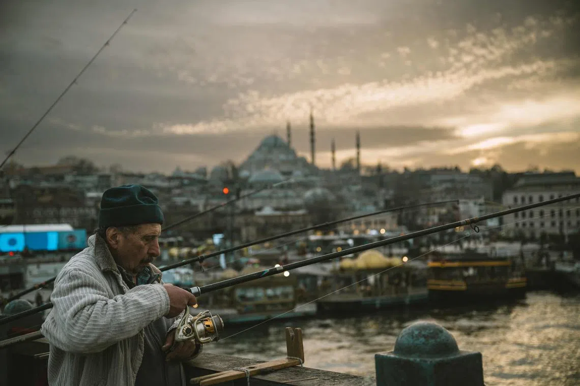 A man fishing on Galata bridge as the Suleymaniye mosque appears in the background in Istanbul on Mar 13, 2025.