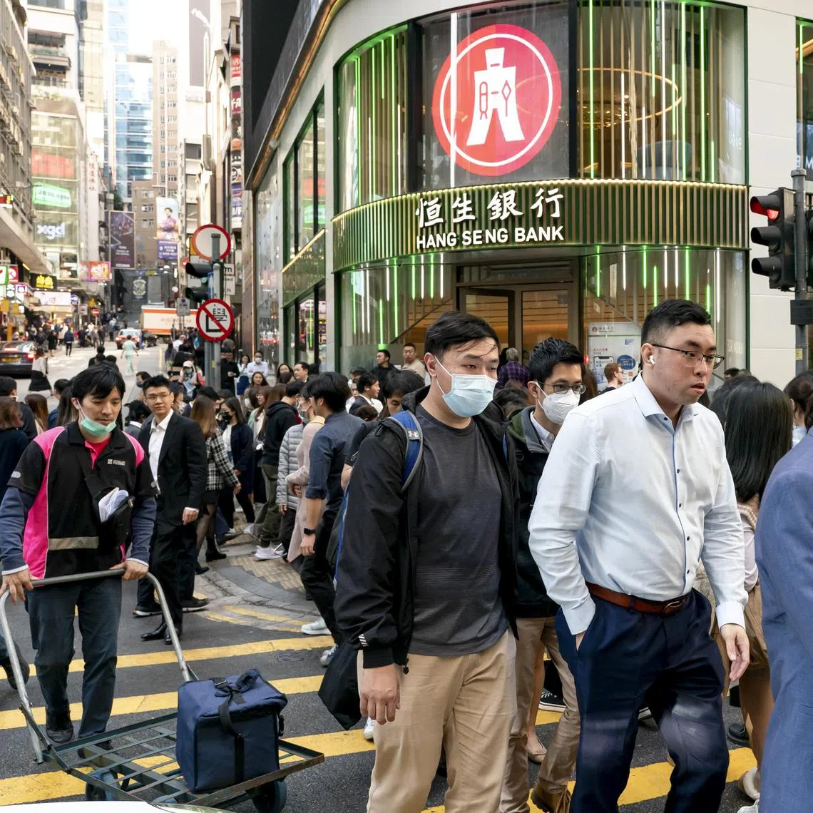 Office workers cross a street in Central, a major financial district in Hong Kong, on Jan 15, 2024. About 55,000 Chinese from the mainland have joined Hong Kong’s working masses through a “top talent” visa program since December 2022. (Anthony Kwan/The New York Times)