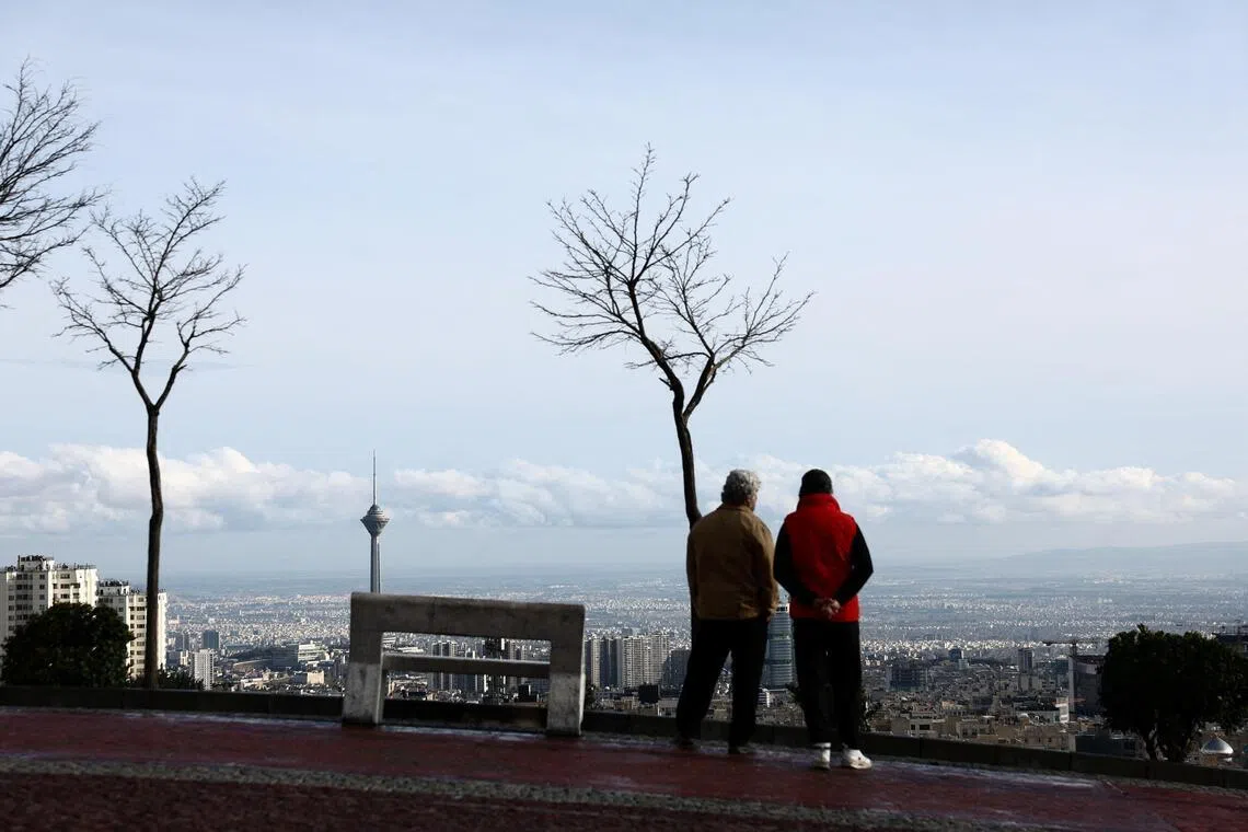 People stand at a park with a view of Milad Tower in Tehran, Iran.