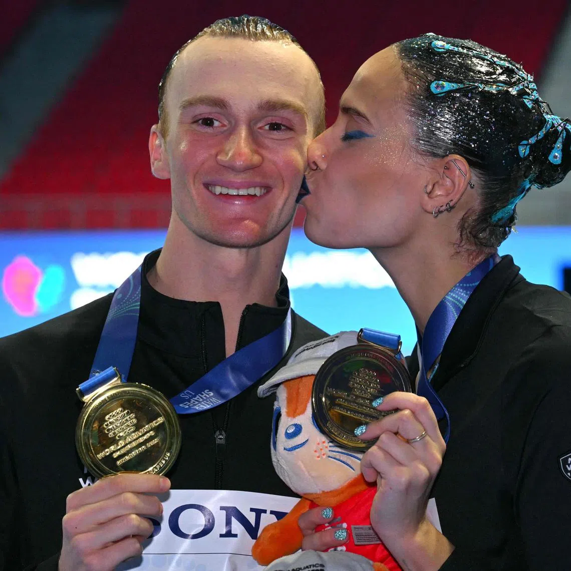 Neutral Athlete artistic swimmer Mayya Gurbanberdieva (R) and Neutral Athlete artistic swimmer Aleksandr Maltsev celebrate with their gold medals after the final of the mixed duet technical artistic swimming event during the 2025 World Aquatics Championships in Singapore on July 23, 2025. (Photo by François-Xavier MARIT / AFP)