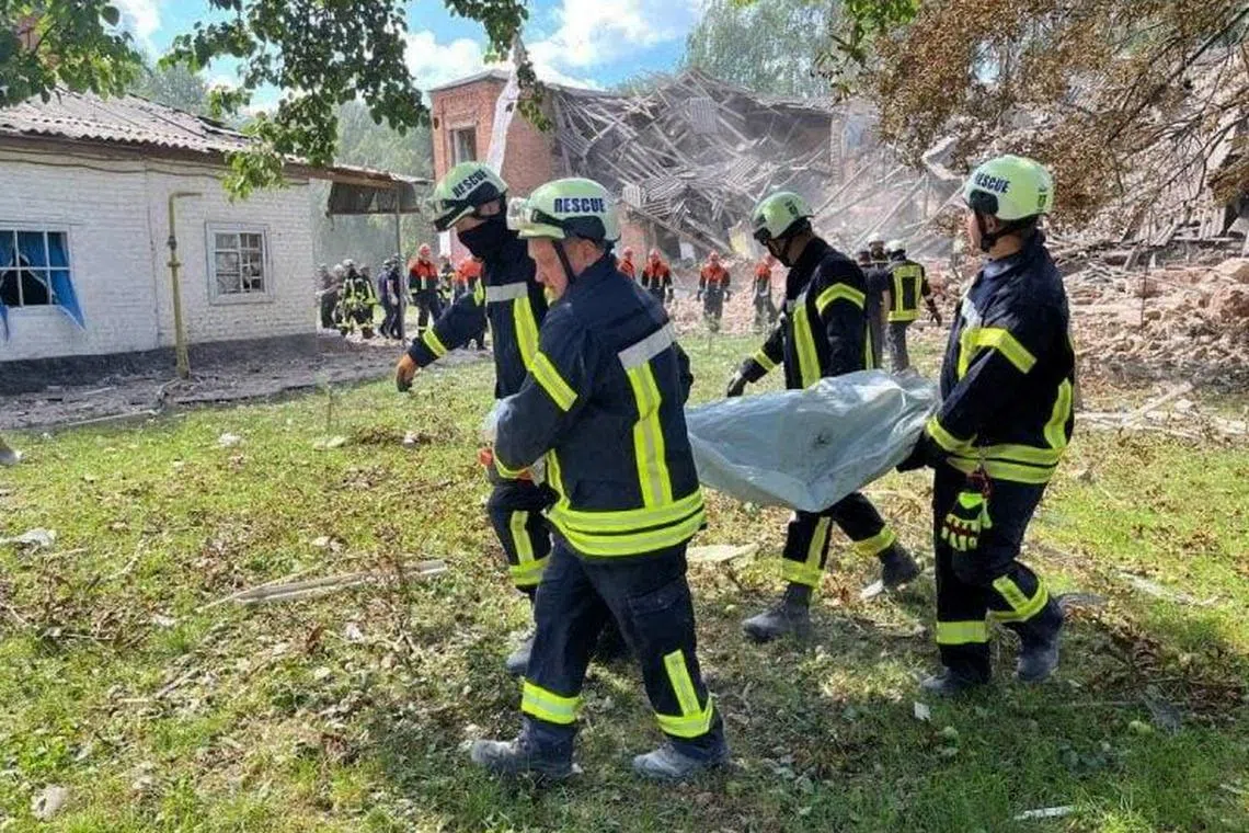 Rescuers carrying the body of a victim from the destroyed school in Romny, in Ukraine's Sumy region.