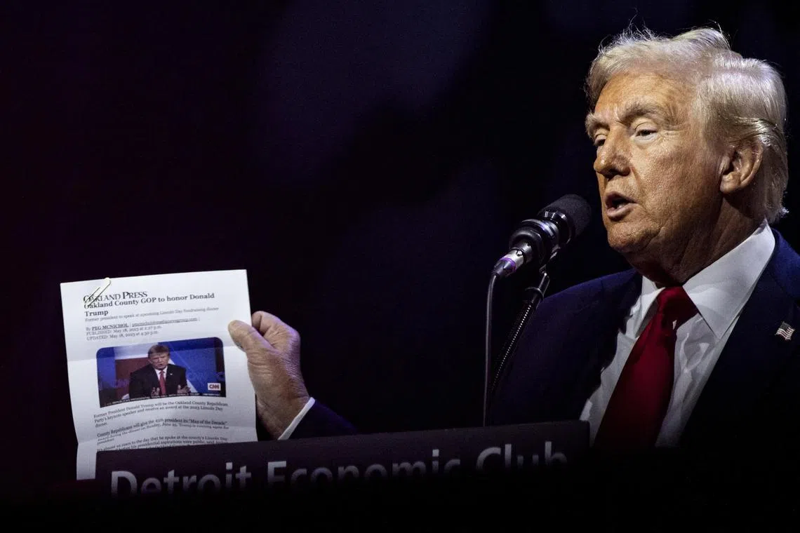 Former President Donald Trump holds up an article from The Oakland Press during a campaign event with the Detroit Economic Club in Detroit on Oct 10