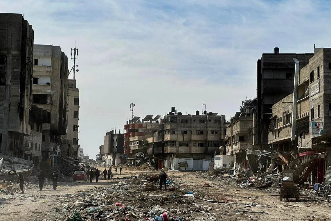 FILE PHOTO: People walk near damaged houses at Zeitoun neighborhood after Israeli forces withdrew from the area, in Gaza City March 1, 2024. REUTERS/Hossam Azam/File Photo