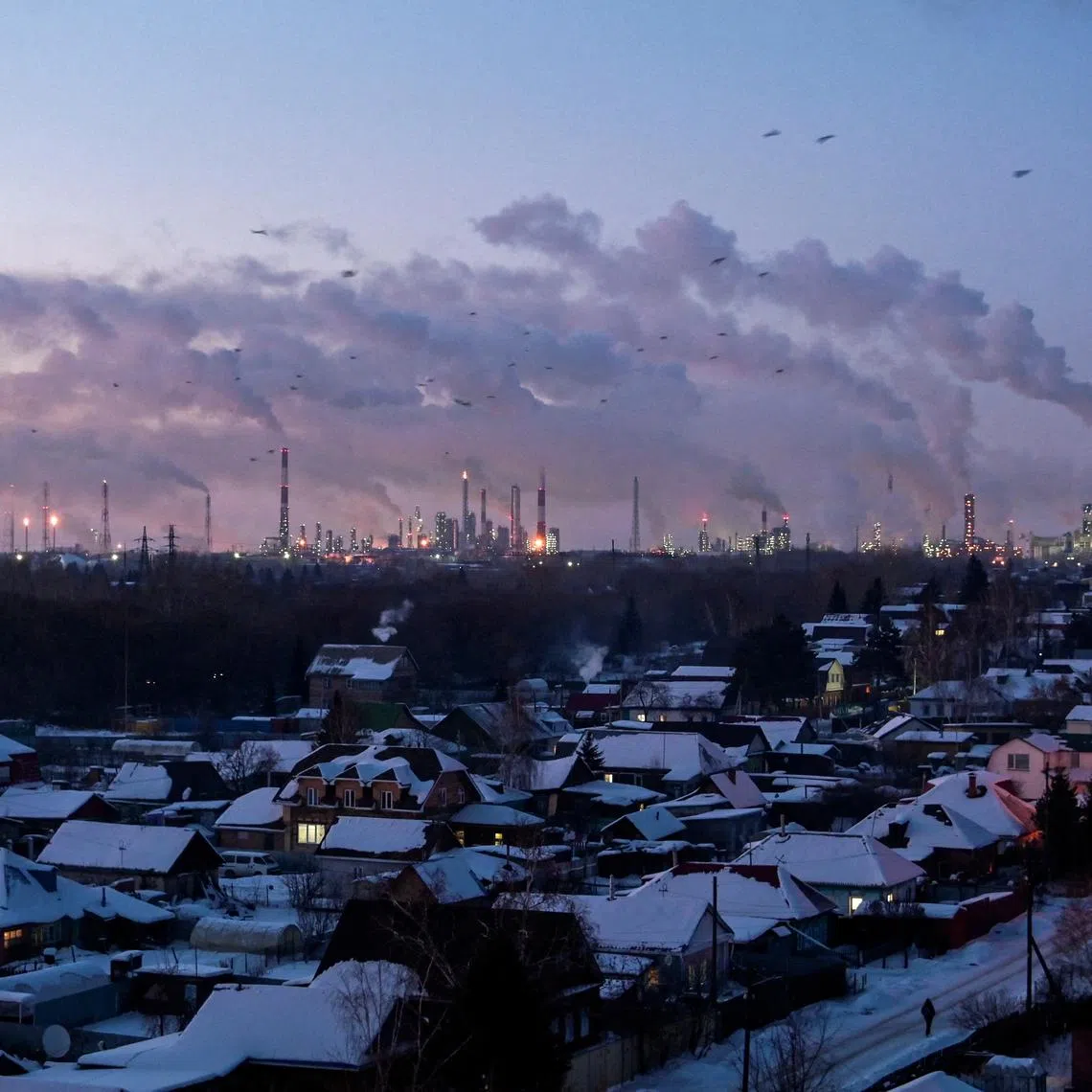 FILE PHOTO: Birds fly above buildings as flue gas and steam rise out of chimneys and smokestacks of an oil refinery during sunset on a frosty day in the Siberian city of Omsk, Russia, February 8, 2023. REUTERS/Alexey Malgavko/File Photo