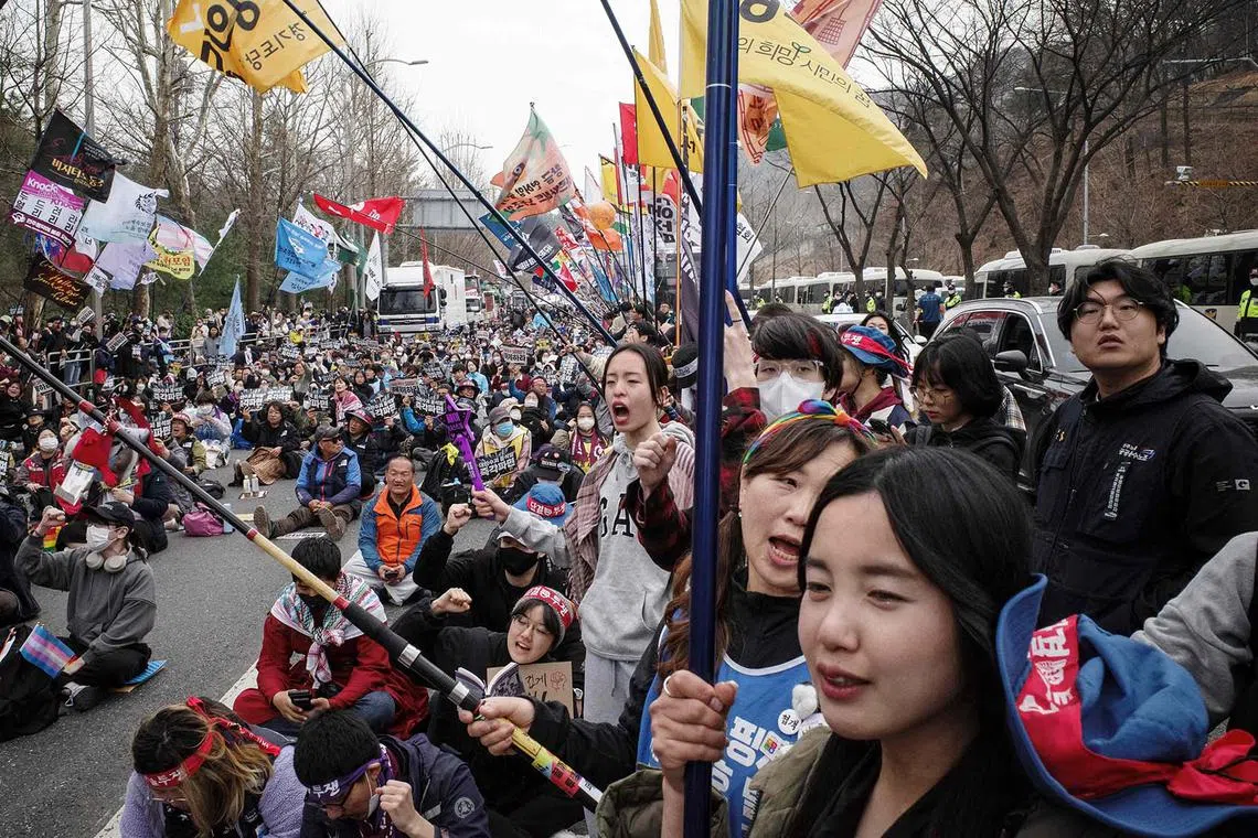 TOPSHOT - Members of the Korean Peasants League, many of them farmers from rural provinces, and others shout slogans and hold flags during a protest against impeached South Korea President Yoon Suk Yeol in Seoul on March 25, 2025. (Photo by ANTHONY WALLACE / AFP)
