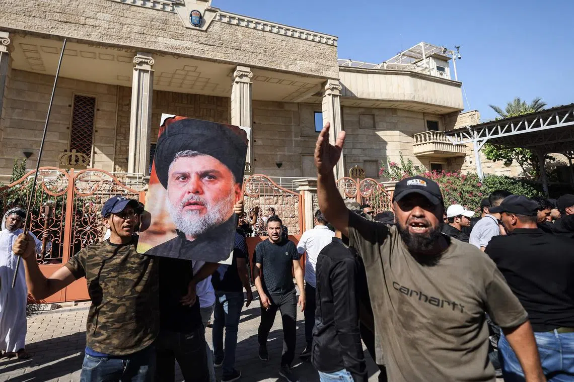 A supporter of Moqtada Sadr raises a picture of the Shi'ite Muslim leader, as others demonstrate inside the courtyard of the Swedish embassy in Baghdad.