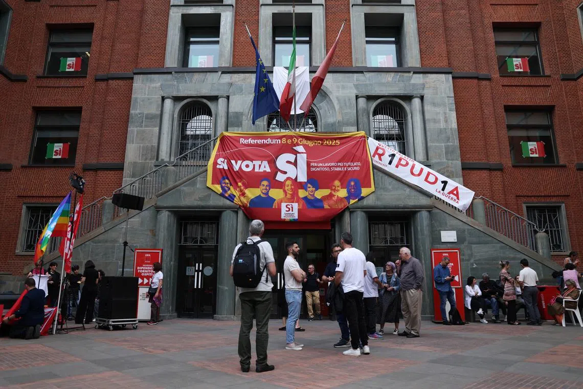People stand next to a banner in favour of five abrogative popular referendums on employment and Italian citizenship, in Milan, Italy, June 4, 2025. REUTERS/Claudia Greco