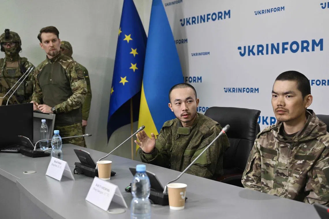 Captured Chinese nationals Zhang Renbo (centre) and Wang Guangjun (right) look on during a press conference in Kyiv on April 14.
