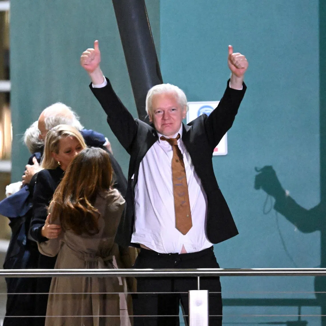 WikiLeaks founder Julian Assange gestures at supporters after arriving at Canberra Airport, Canberra, Australia June 26, 2024. AAP Image/Lukas Coch via REUTERS