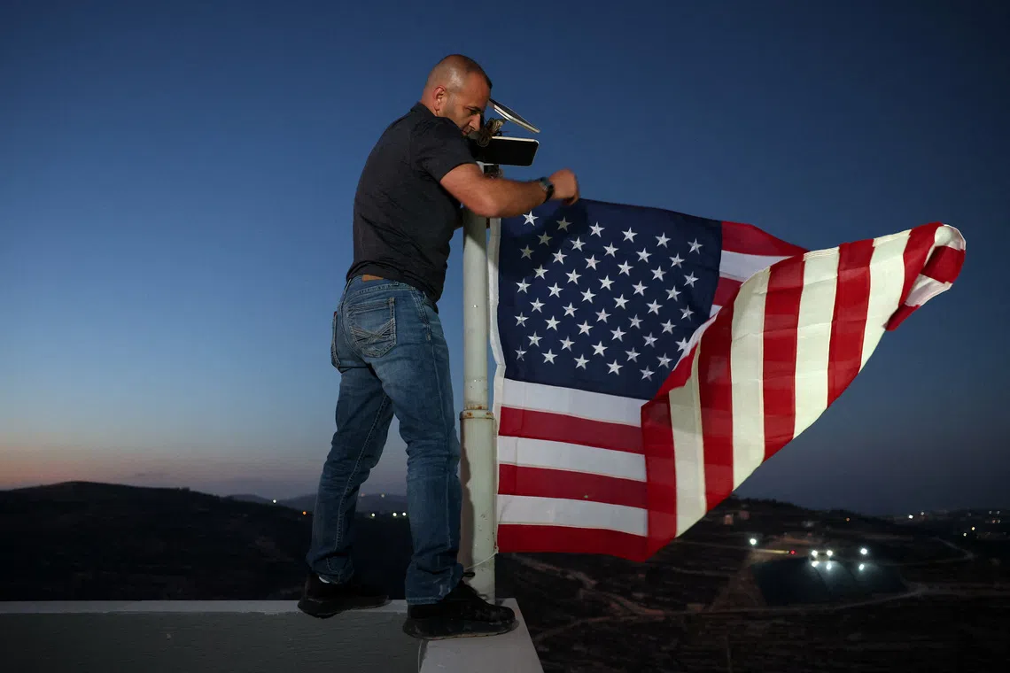 Palestinian-American Loui Ridi, whose home in the Israeli-occupied West Bank has been encircled by militant settlers for more than a week, hangs a U.S. flag after gaining access to his besieged home, in Qusra, Israeli-occupied West Bank, August 17, 2026. REUTERS/Ammar Awad