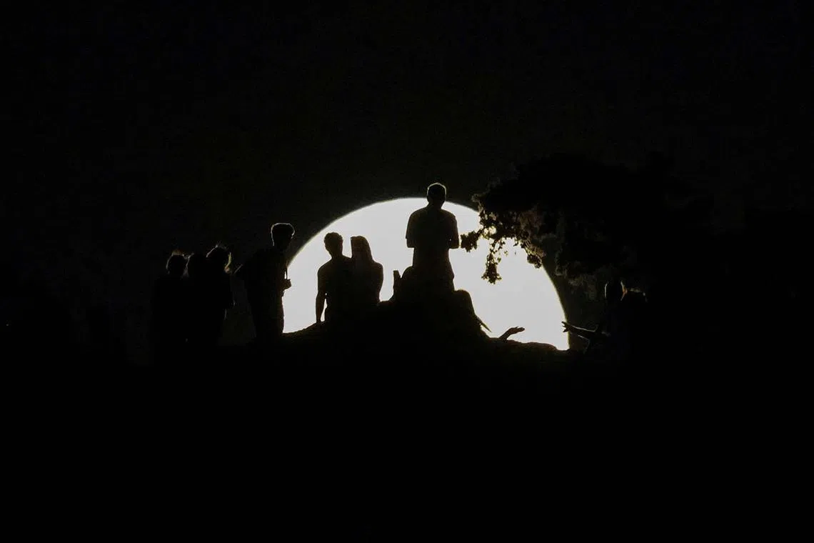 People watching the rising “Strawberry Moon” from Areopagus Hill in Athens, Greece, June 10, 2025.