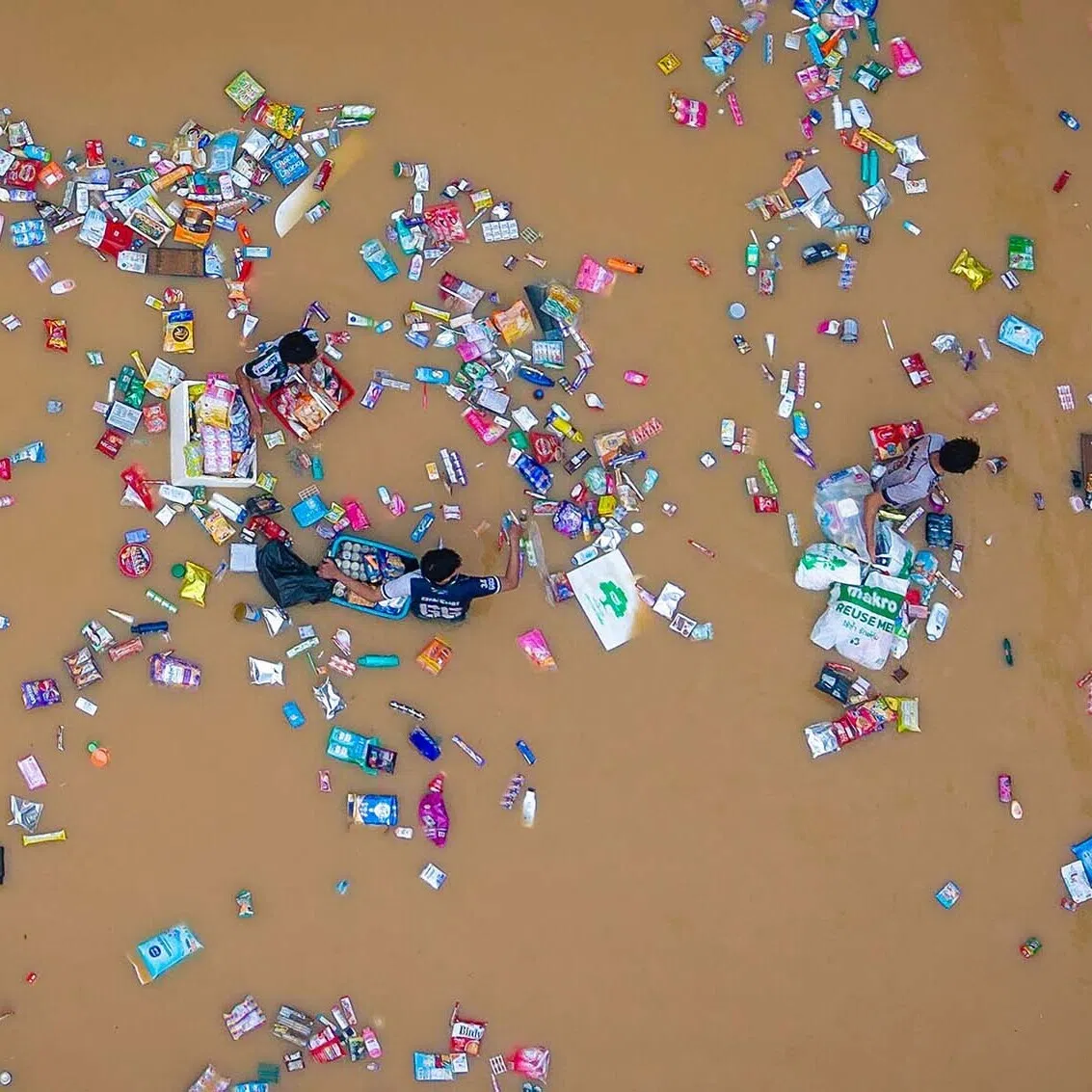People surrounded by floating products from a supermarket as they wade through flood waters in Hat Yai in Thailand's southern Songkhla province, as severe flooding affected thousands of people in the country's south following days of heavy rain, Nov 26, 2025. 