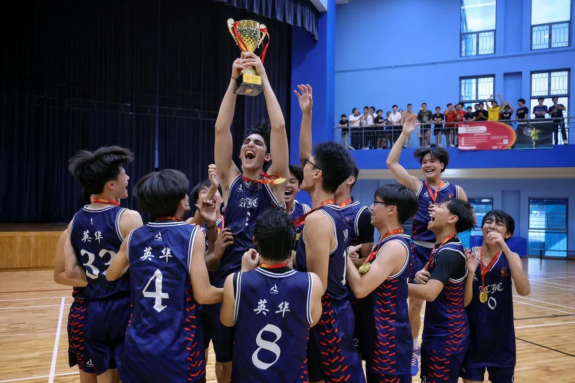 O capitão Eshan Kaul, do Anglo-Chinese Junior College, segurando o troféu no alto, enquanto seus companheiros de equipe comemoram sua vitória sobre o Raffles Institution nos Jogos Nacionais da Escola, uma final de basquete para meninos da Div no Jurong East Sports Hall em 23 de maio de 2025.