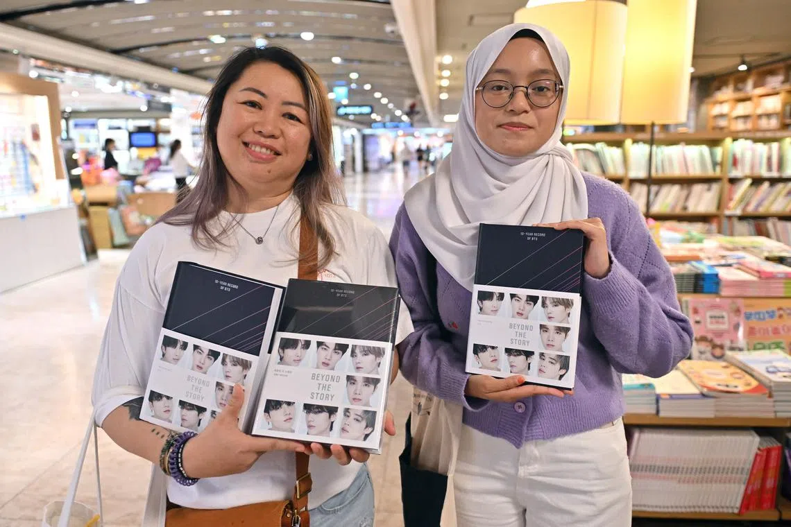 BTS' Malaysian fans Aiudrey (L) and Aqilah (R) hold copies of the BTS memoir titled Beyond The Story: 10-Year Record Of BTS at a bookstore in Seoul on July 9, 2023. K-pop megastars BTS released a hot-anticipated memoir in South Korea on July 9, to mark their 10th anniversary. 