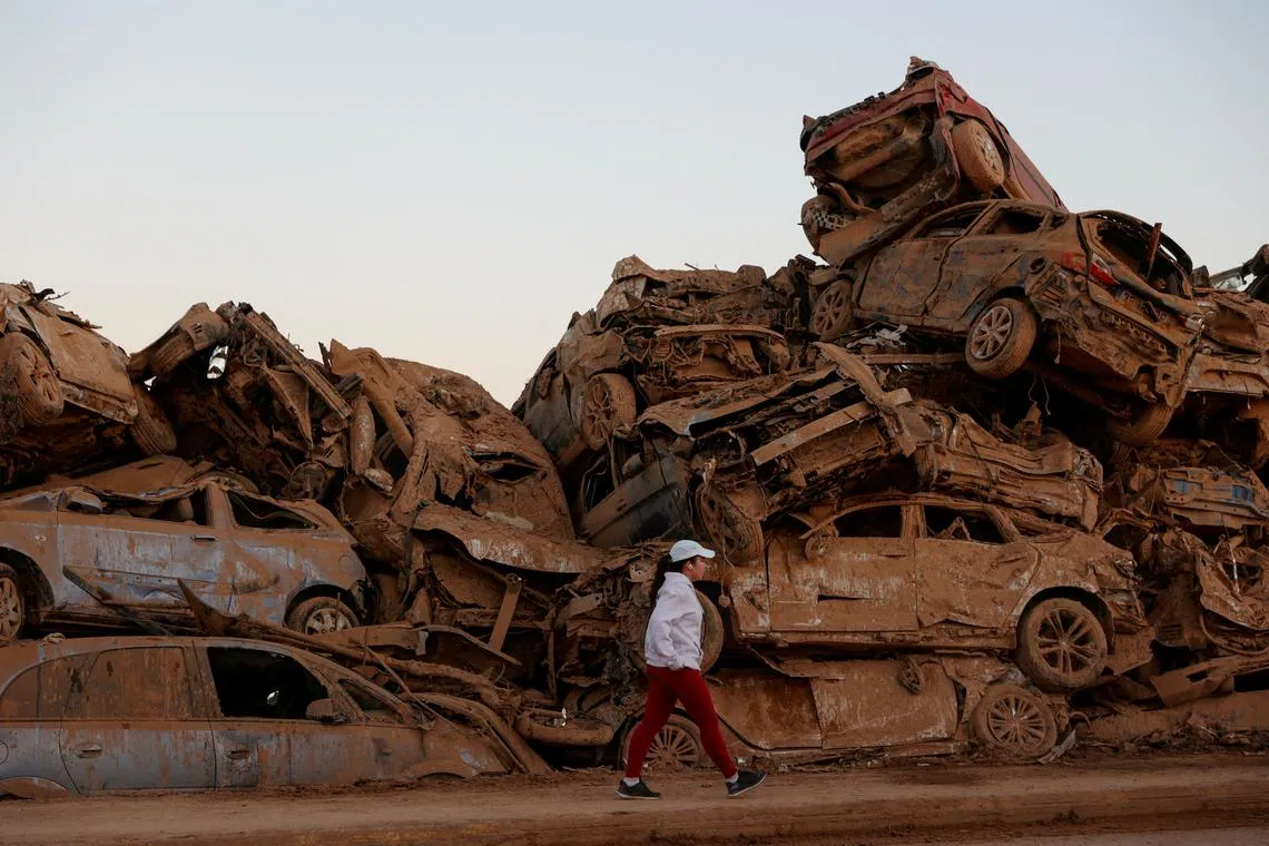 FILE PHOTO: Nearly a month after severe flooding, a person walks past a field where water-ravaged cars are piled up in Paiporta, Valencia, Spain, November 28, 2024. REUTERS/Eva Manez/File Photo