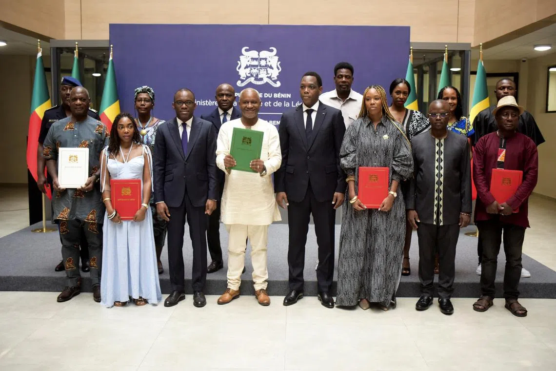 Isaline Attely (3rd from R), an Afro-descendant from Martinique, and other Afro-descendants, who obtained their Beninese nationality, pose for a photograph with Benin's Foreign Minister Olushegun Adjadi Bakari and other Beninese officials, during a naturalisation ceremony in Cotonou, Benin, December 27, 2025. REUTERS/Charles Tossou Placide