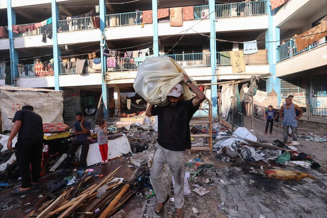 A Palestinian man carrying items wrapped in plastic following an Israeli strike at a school sheltering displaced Palestinians, in the Al-Bureij camp, in the central Gaza Strip, on July 8.