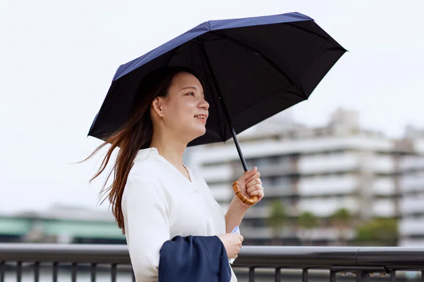 Best UV umbrellas in Singapore: Woman carrying an umbrella to shade herself on a cloudy day.