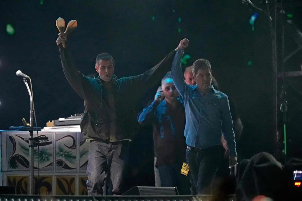Liam Gallagher (left) and Noel Gallagher of British rock band Oasis take to the stage at the Principality Stadium in Cardiff on July 4, 2025, for the opening concert of their highly anticipated reunion tour nearly 16 years after last performing together. 