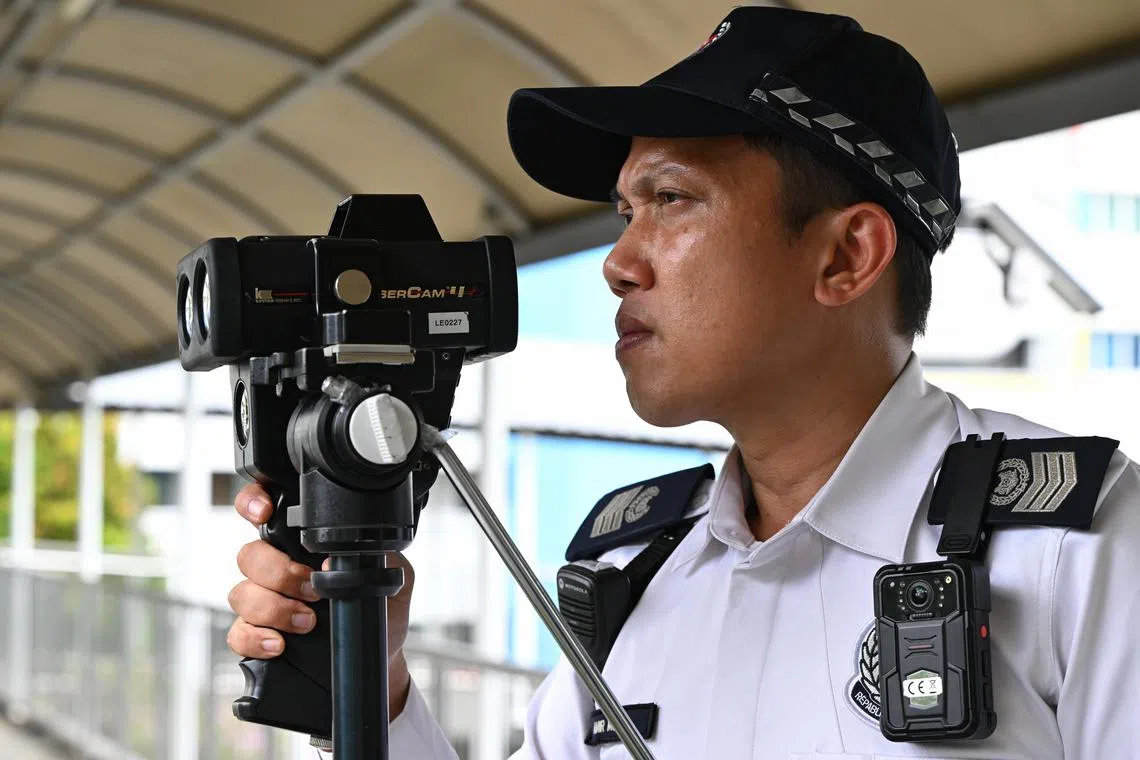A traffic policeman using a police speed laser camera over PIE during a media showcase on Feb 22.
