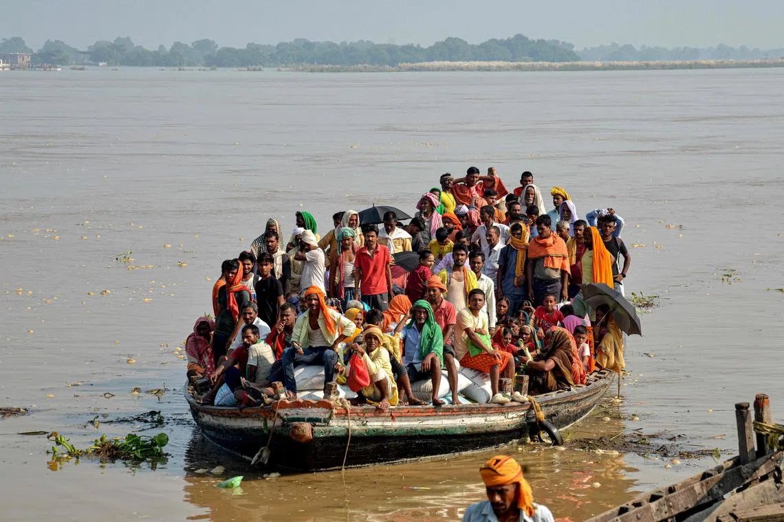 TOPSHOT - Flood-affected people along with their belongings, move to a safer place in a boat after rise in the water level of river Ganges following heavy rains, in Patna on September 23, 2024. (Photo by Sachin KUMAR / AFP)