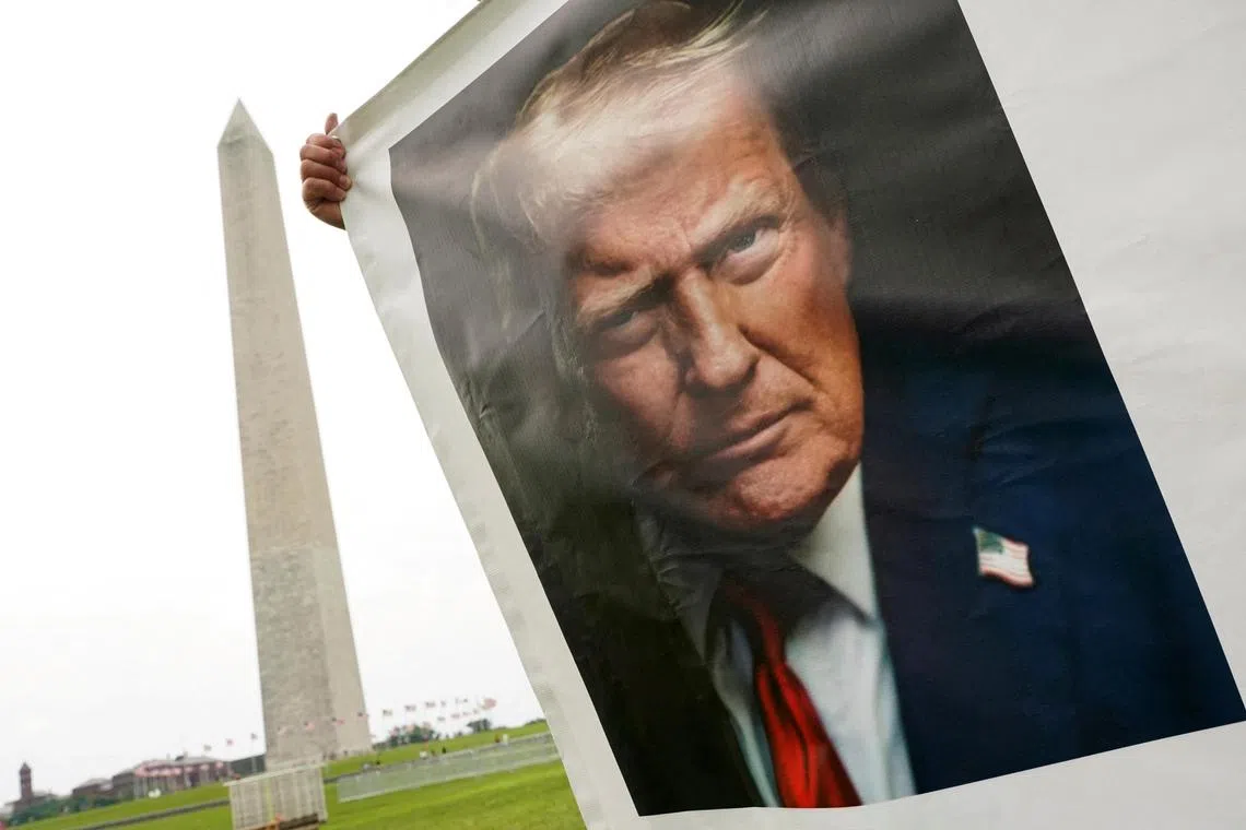 A supporter holds a banner with U.S President Donald Trump's picture near the Washington Monument, ahead of the upcoming U.S. Army 250th anniversary celebration parade, in Washington, D.C., U.S., June 13, 2025. REUTERS/Nathan Howard     TPX IMAGES OF THE DAY     