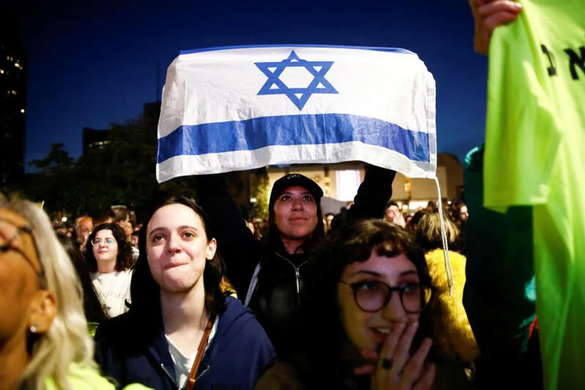 People react as they watch news coverage of the release of Romi Gonen, Doron Steinbrecher and Emily Damari, three female hostages who have been held in Gaza since the deadly October 7 2023 attack, as part of a ceasefire deal in Gaza between Hamas and Israel, in Tel Aviv, January 19, 2025. REUTERS/Shir Torem