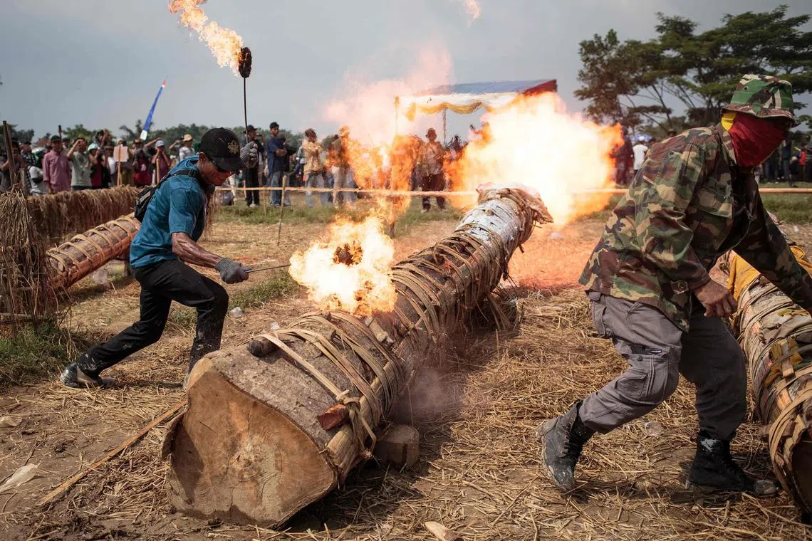 Participants fire traditional cannons and make explosive sounds during the Kuluwung festival, held annually few days after Eid al-Fitr, in Bogor, West Java, on April 14, 2024. Villagers prepare hollow tree trunks to create explosions by firing carbide like a cannon to compete the sounds between two villages about ten kilometres apart across a river. (Photo by ADITYA AJI / AFP)