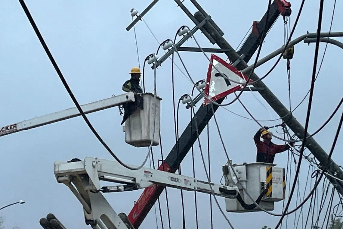 Utility workers trying to repair power lines downed by the high winds from Typhoon Koinu in Taiwan's southern Pingtung County on Oct 5.