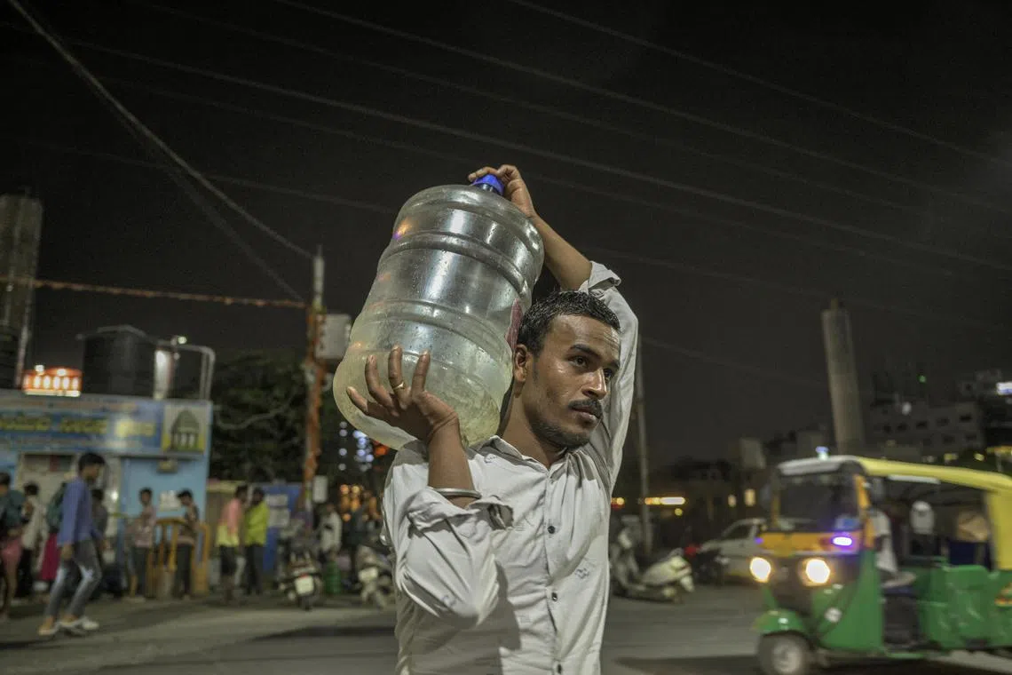 A resident carries a container with subsidised water in Bengaluru, India, on March 19, 2024.
