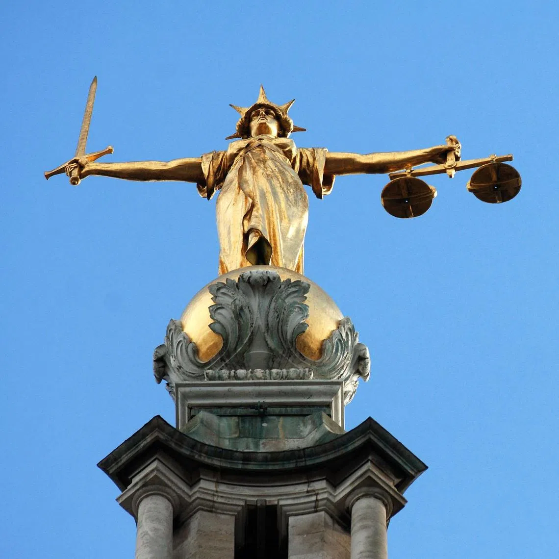 View of the gold statue of the figure of justice, holding scales and a sword, on top of the Central Criminal Court, also referred to as Old Bailey, in central London.