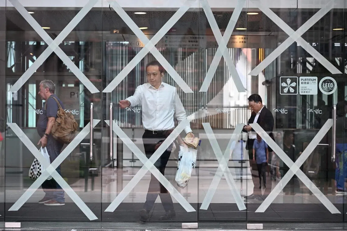 A shopper exiting a shopping mall with taped up windows as Super Typhoon Ragasa approaches Hong Kong on Sept 23. 2025.