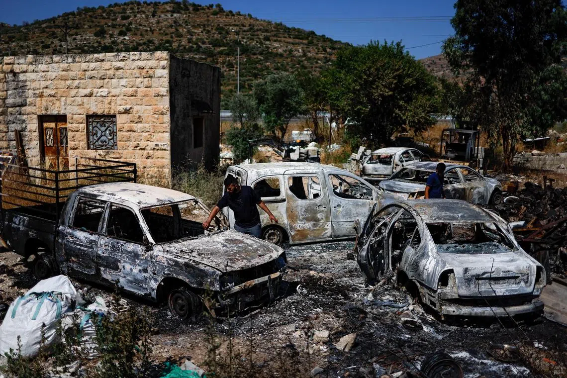 Palestinians check burnt vehicles after Israeli settlers attack near Ramallah in the Israeli-occupied West Bank on June 21.
