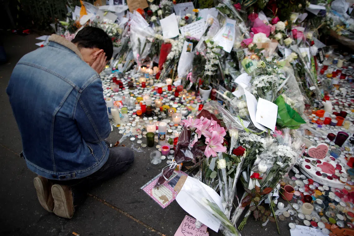 FILE PHOTO: A man kneels as he pays tribute to victims near the site of the attack at the Bataclan concert hall in Paris, November 16, 2015.    REUTERS/Christian Hartmann/File Photo