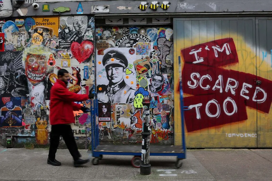 A worker walks past street art posters depicting Tesla CEO Elon Musk in World War Two Nazi German uniform, in Brick Lane, east London, Britain, March 25, 2025. REUTERS/Isabel Infantes TPX IMAGES OF THE DAY