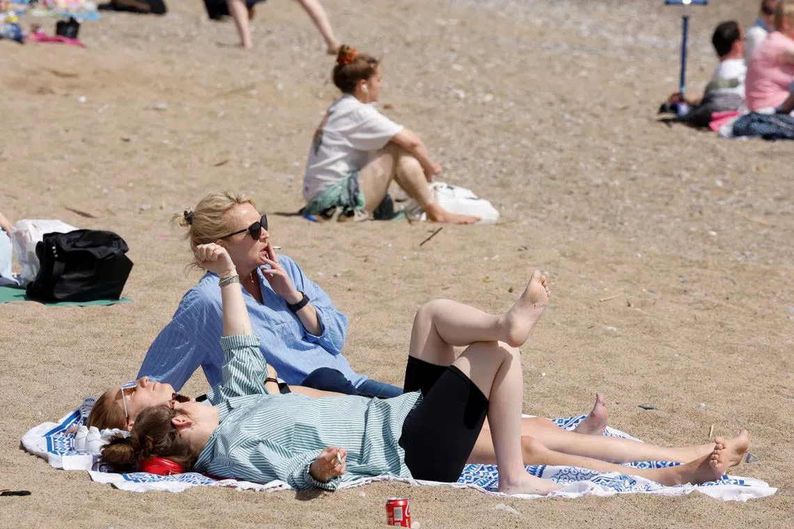 FILE PHOTO: Women smoke at Sant Sebastia beach, in Barcelona, Spain, April 8, 2022. REUTERS/Albert Gea/File Photo