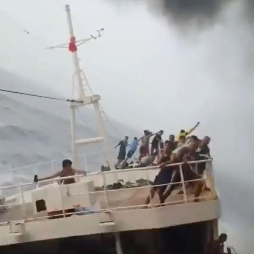 Crew members on the smaller Chinese fishing vessel hold on to railings as the ship appears to tilt significantly to its side.