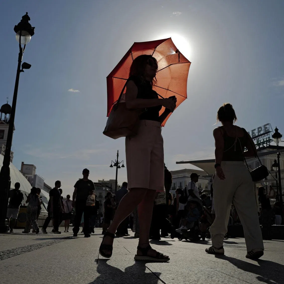 A woman with an umbrella walks at Plaza Puerta del Sol during a spring heatwave in Madrid, Spain, on May 27.
